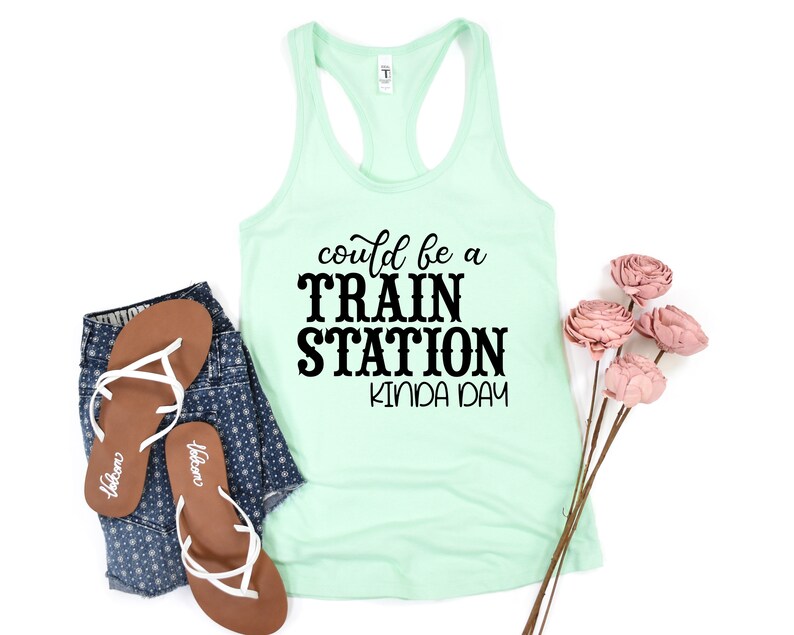 May include: A light green tank top with the text "could be a TRAIN STATION kinda day" in black lettering.