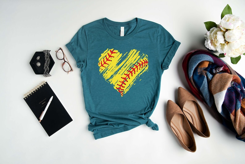 May include: Teal blue t-shirt with a yellow and red softball design in the shape of a heart.