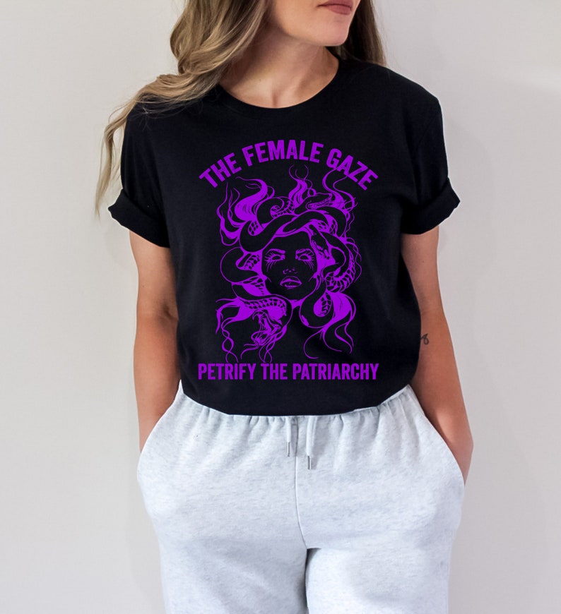 May include: Black t-shirt with a purple graphic of Medusa's head with snakes for hair. The text "The Female Gaze" is above the graphic and "Petrify the Patriarchy" is below.