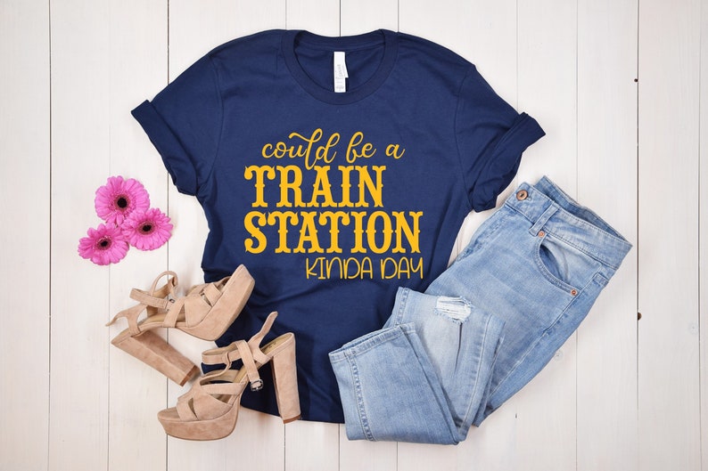 May include: A navy blue t-shirt with the text "could be a TRAIN STATION kinda day" in yellow lettering.
