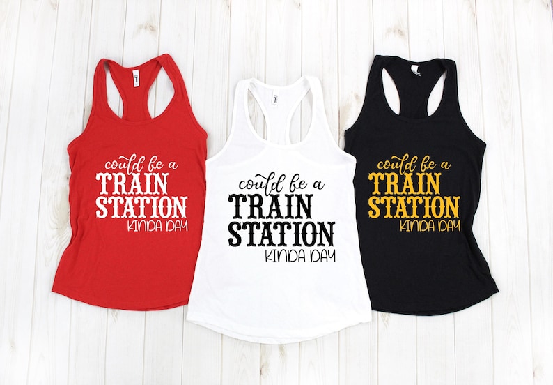 May include: Three tank tops with the text "could be a train station kinda day" printed on them. The tank tops are red, white, and black.