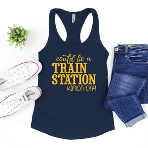 May include: A navy blue tank top with the text "could be a TRAIN STATION kinda day" in yellow lettering.
