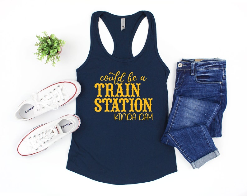 May include: A navy blue tank top with the text "could be a TRAIN STATION kinda day" in yellow lettering.