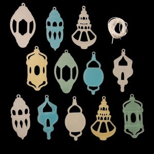 May include: A set of 12 decorative paper lanterns in various colors and designs, including a crescent moon, stars, and geometric patterns. The lanterns are cut out and ready to be strung together for a festive display.