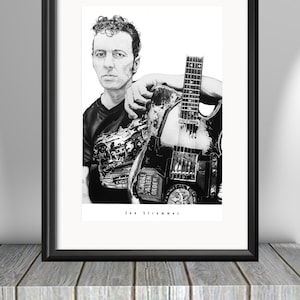 Może przedstawiać: Czarno-biały rysunek Joe Strummera, wokalisty The Clash, trzymającego gitarę. Gitara ma naklejkę z napisem "Ignore Alien Order".