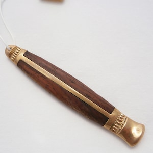 May include: A wooden and gold pen with a gold cap and a white string attached to it.