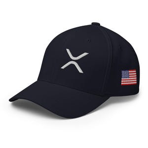 May include: Navy blue baseball cap with a white embroidered XRP logo on the front and a small American flag patch on the side. The cap has a curved brim and a structured fit.