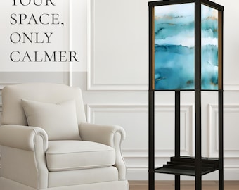 May include: A tall, square floor lamp with a black frame and a shade featuring an abstract watercolor design in shades of blue, white, and gold. The text "YOUR SPACE, ONLY CALMER" is visible on the left side of the image.