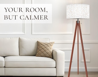 May include: A floor lamp with three wooden tripod legs and a cylindrical white lampshade featuring a thin, dark grid pattern. The text "YOUR ROOM, BUT CALMER" is displayed in dark brown lettering on the left side of the image.
