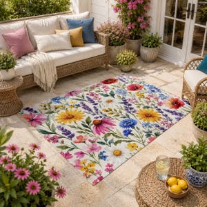 May include: A rectangular area rug featuring a vibrant, multi-colored floral pattern on a white background. The design includes illustrations of yellow sunflowers, pink coneflowers, white daisies, blue cornflowers, and purple lavender sprigs.