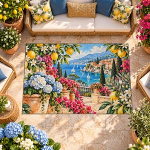 May include: A rectangular area rug featuring a coastal Mediterranean scene with a stone terrace, blue hydrangeas, pink bougainvillea, and lemon branches. The view includes a blue sea with sailboats, distant mountains, and a hillside village.