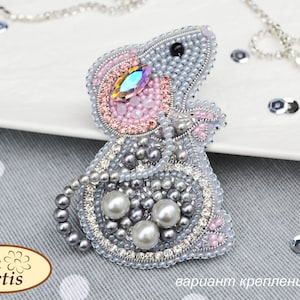May include: A beaded mouse brooch with pink, gray, and silver beads. The mouse has a large, iridescent crystal for an eye. The brooch is attached to a silver chain.