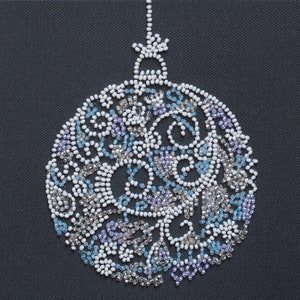 Op de afbeelding: Een witte en blauwe kerstbal van kralen in de vorm van een cirkel met een ster bovenop.