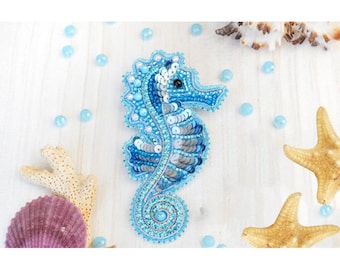 Può includere: Un fermaglio a forma di cavalluccio marino in perle blu e argento. Il cavalluccio marino è fatto di paillettes e perline e ha un design dettagliato.