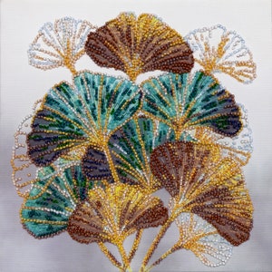 Könnte beinhalten: Nahaufnahme eines Perlenkunstwerks, das eine Ansammlung von Ginkgoblättern in Braun-, Grün- und Weißtönen darstellt. Die Blätter sind fächerförmig angeordnet und bilden ein optisch ansprechendes und komplexes Design.