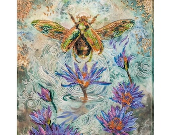 Può includere: Un'opera d'arte in perline colorate che raffigura uno scarabeo verde e marrone che vola sopra uno stagno con ninfee viola. Lo sfondo è un acquerello blu chiaro e verde.