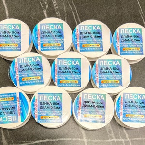 May include: A collection of white spools of fishing line, each labeled with the text "LESKA" and details about the length and diameter of the line in millimeters. The spools are labeled in Russian.