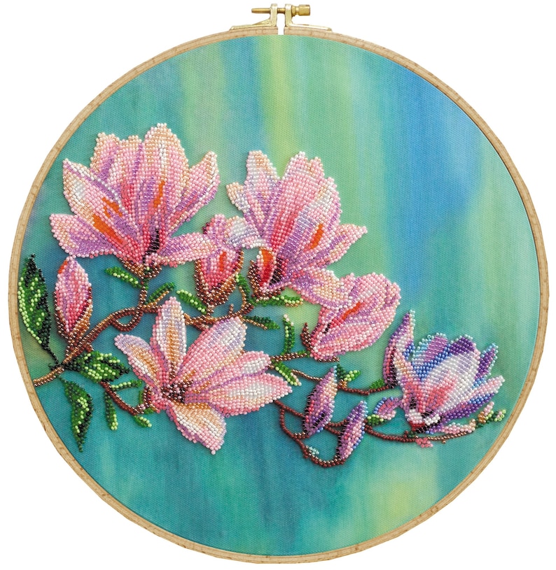 May include: A close-up of a beaded embroidery depicting pink magnolia flowers against a blue and green background. The flowers are clustered together and have a delicate, feminine feel.