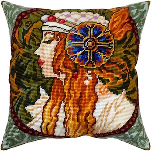 May include: A colorful embroidered pillow featuring a woman's profile with long red hair and a floral headdress. The background is a green and brown floral pattern.