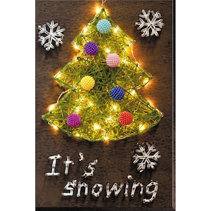 May include: A string art Christmas tree with lights and colorful ornaments. The tree is on a brown wooden background with the words "It's snowing" written below it.