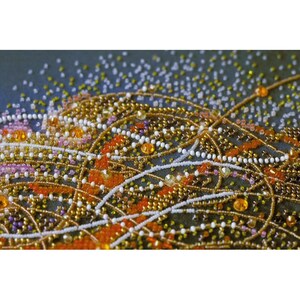 May include: Close-up of a beaded design with a variety of colors, including orange, gold, white, and pink. The beads are arranged in a swirling pattern, creating a textured and intricate design.