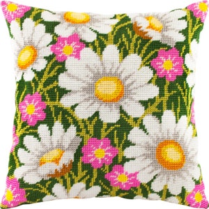 May include: A white pillow with a green background and a floral pattern of white daisies with yellow centers and pink flowers with yellow centers.