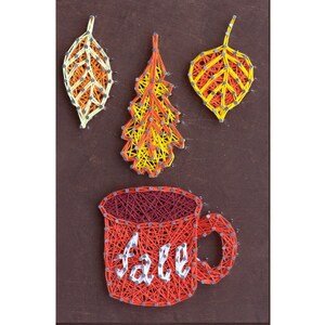 Puede incluir: Arte de hilo de una taza de café roja con la palabra "otoño" en hilo blanco. La taza está rodeada de tres hojas hechas de hilo amarillo, naranja y rojo.