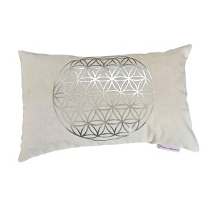 Könnte beinhalten: Ein rechteckiges cremefarbenes Kissen mit einem silbernen geometrischen Lebensblumen-Design. Das Kissen hat eine weiche, plüschige Textur und ein kleines rosa Etikett. Dieses dekorative Kissen ist für die Inneneinrichtung geeignet, ca. 40 cm x 25 cm.