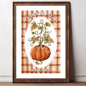 Peut inclure: Impression encadrée avec une illustration à l'aquarelle d'une citrouille et de feuilles. Le texte indique "Pumpkin Patch" et "Since 1802". L'arrière-plan présente un motif à carreaux dans des tons orange et marron.