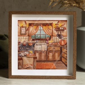 May include: A framed watercolor painting depicts a cozy kitchen scene with autumn decor. The artwork features a stove, sink, and cabinets in warm tones, with a pumpkin and fall leaves. The text "Fall in Love" is visible on a small framed picture.