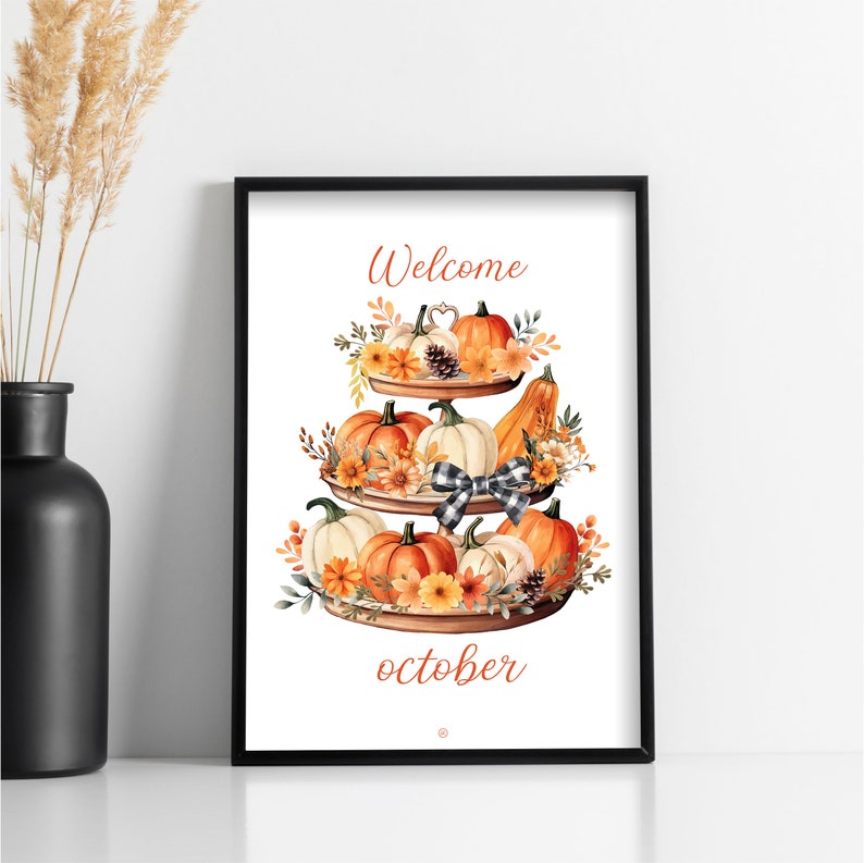 May include: A framed print featuring a tiered tray decorated with pumpkins, flowers, and a buffalo check bow. The words "Welcome" and "october" are written in a decorative font. The artwork is set against a white background.