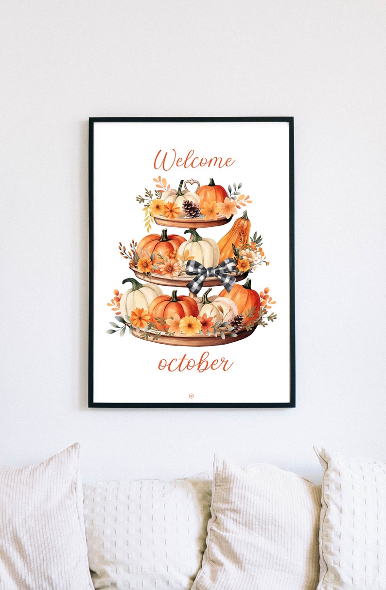 May include: A framed print featuring a tiered display of pumpkins, gourds, and flowers. The artwork has the words "Welcome" and "October" in orange script. A black and white checkered bow is in the center.