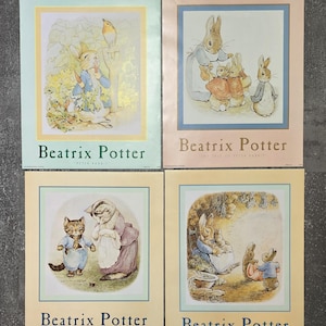May include: Four rectangular prints featuring Beatrix Potter illustrations. Each print displays a classic storybook scene with rabbits or kittens, framed by a colored border and the text Beatrix Potter at the bottom, identifying specific tales.