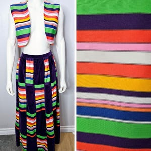 May include: A vintage two-piece outfit comprising a vest and a long skirt. The vest is sleeveless and cropped, with horizontal stripes in various colours. The skirt is a deep purple with vertical stripes in coordinating colours. The fabric appears to be velvet.
