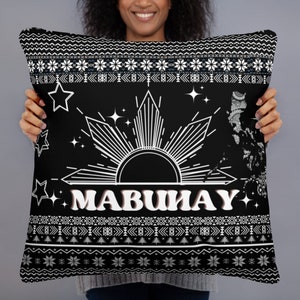 May include: Black decorative pillow with a white graphic of a sunburst, stars, and the word "MABUHAY". The pillow also features a map outline and a patterned border with snowflakes and geometric shapes.