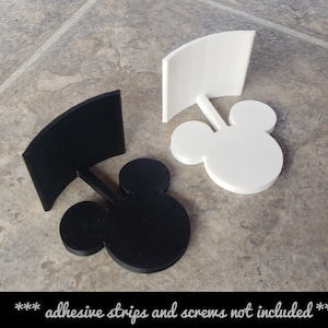 May include: Two 3D printed Mickey Mouse head wall mounts, one black and one white. The mounts are designed to hold a flat surface, such as a picture frame or a sign. *** adhesive strips and screws not included ***