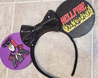 May include: Black headband with a purple and black ear featuring a cartoon character and a black ear with the text "HELLFIRE" and yellow flames.