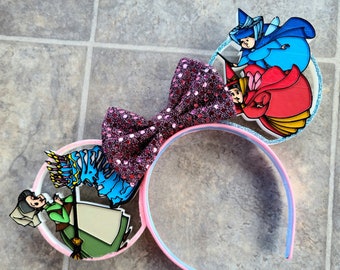 May include: Pink and blue Minnie Mouse ears with a sparkly pink bow and a 3D design featuring Cinderella, Prince Charming, and the Fairy Godmother.