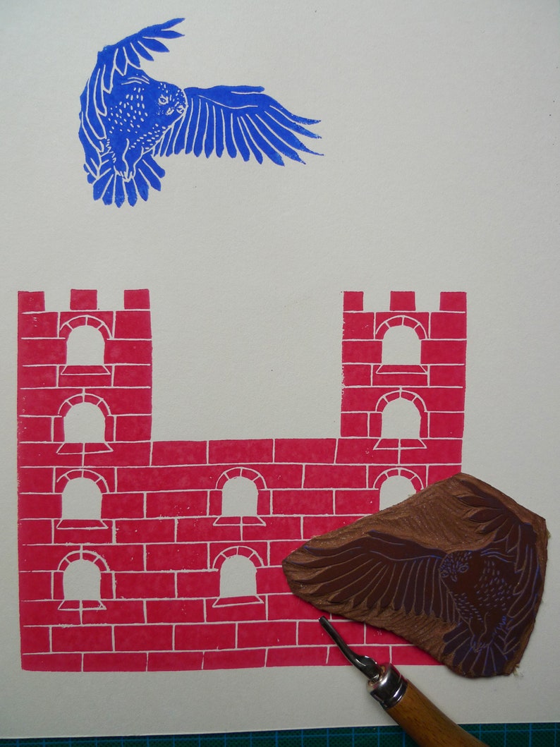May include: A red brick castle with five arched windows and a brown wooden carving of an owl with outstretched wings. The carving is used to create a print of the owl.