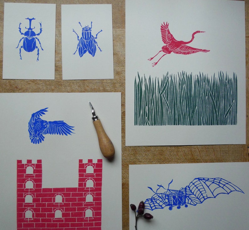 May include: Five different linocut prints on white card stock. The prints are of a beetle, a fly, a crane, a castle, and a bat. The prints are all in blue and red ink.