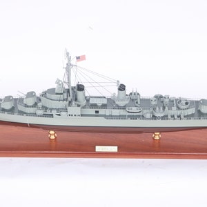 Könnte beinhalten: Ein detailliertes Modell eines US-Navy-Zerstörers, der USS George E. Badger, auf einem Holzsockel. Das Modell ist in einem realistischen Grau lackiert und verfügt über komplizierte Details wie die Schiffsgeschütze, Masten und Takelage.