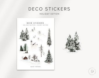 May include: A sheet of stickers featuring a winter wonderland theme. The stickers include a snowy castle, trees, and a small cabin. The text "Deco Stickers Holiday Edition | Snowy Winter" is printed on the sheet.