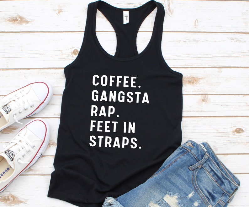 May include: Black tank top with white text that reads "Coffee. Gangsta Rap. Feet in Straps."