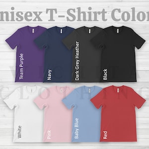 May include: A selection of unisex t-shirts in various colors, including white, team purple, navy, dark grey heather, black, pink, baby blue, and red. The shirts are displayed on a white wood background. Unisex T-Shirt Colors