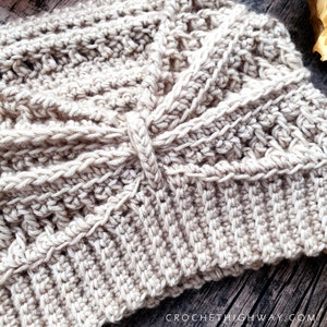 May include: A close-up of a beige crocheted hat with a textured pattern. The hat is made with a single strand of yarn and has a simple, elegant design.