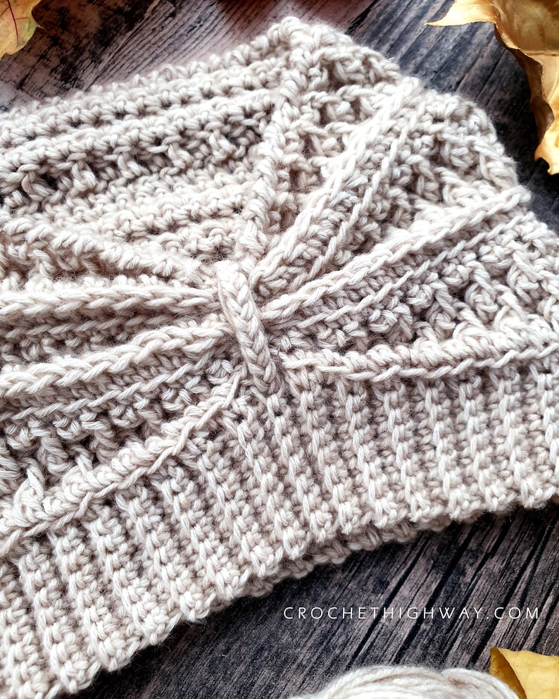 May include: A close-up of a beige crocheted hat with a textured pattern. The hat is made with a single strand of yarn and has a simple, elegant design.