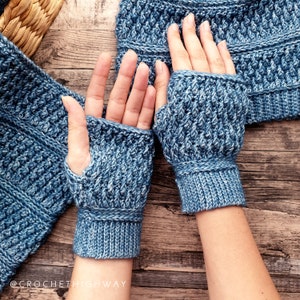 May include: A pair of blue crocheted fingerless gloves with a textured pattern. The gloves are shown on a wooden surface.