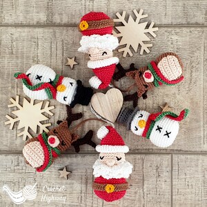 Peut inclure: Un ensemble de sept d&eacute;corations de No&euml;l en crochet, comprenant le P&egrave;re No&euml;l, un bonhomme de neige, un renne et une femme portant un bonnet de P&egrave;re No&euml;l. Les d&eacute;corations sont toutes blanches, rouges et vertes, et elles sont dispos&eacute;es en cercle sur une surface en bois.