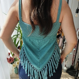 Puede incluir: Un top de crochet de color turquesa con un dise&ntilde;o triangular y ribete de flecos. El top es sin mangas y tiene un escote cuadrado.