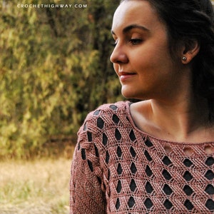 K&ouml;nnte beinhalten: Nahaufnahme einer Frau, die einen rosafarbenen H&auml;kelpullover mit einem Spitzenmuster tr&auml;gt. Der Pullover hat einen runden Ausschnitt und lange &Auml;rmel. Die Frau schaut zur Seite und hat ihre Haare nach hinten gebunden.